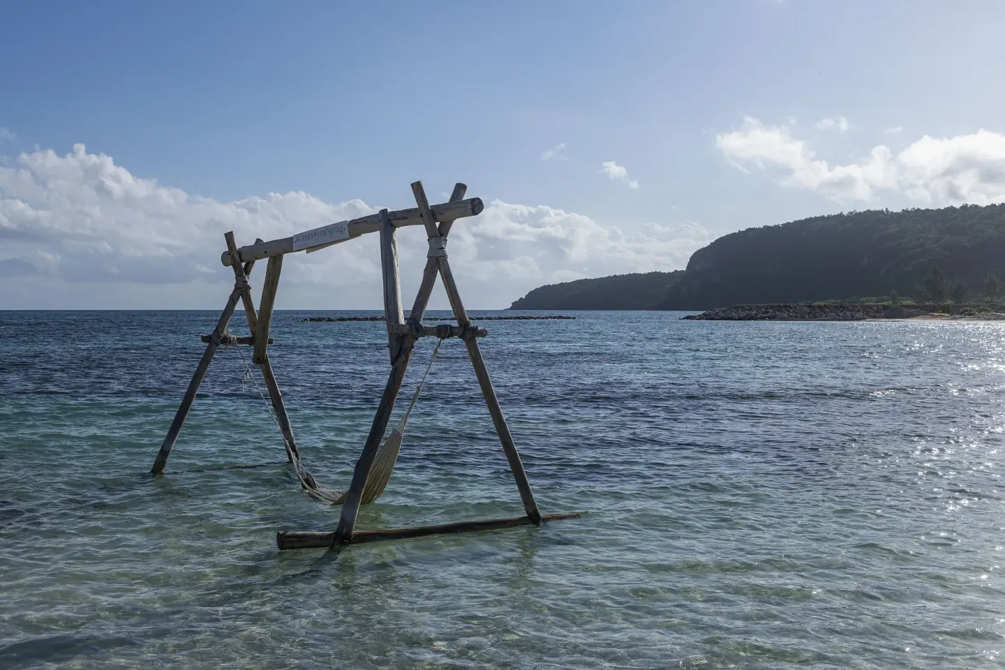 A wooden swing stands in shallow ocean water by the beach at Ocean Eden Bay.