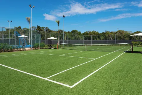 Outdoor tennis court with net, fencing, and light poles at Ocean Eden Bay.