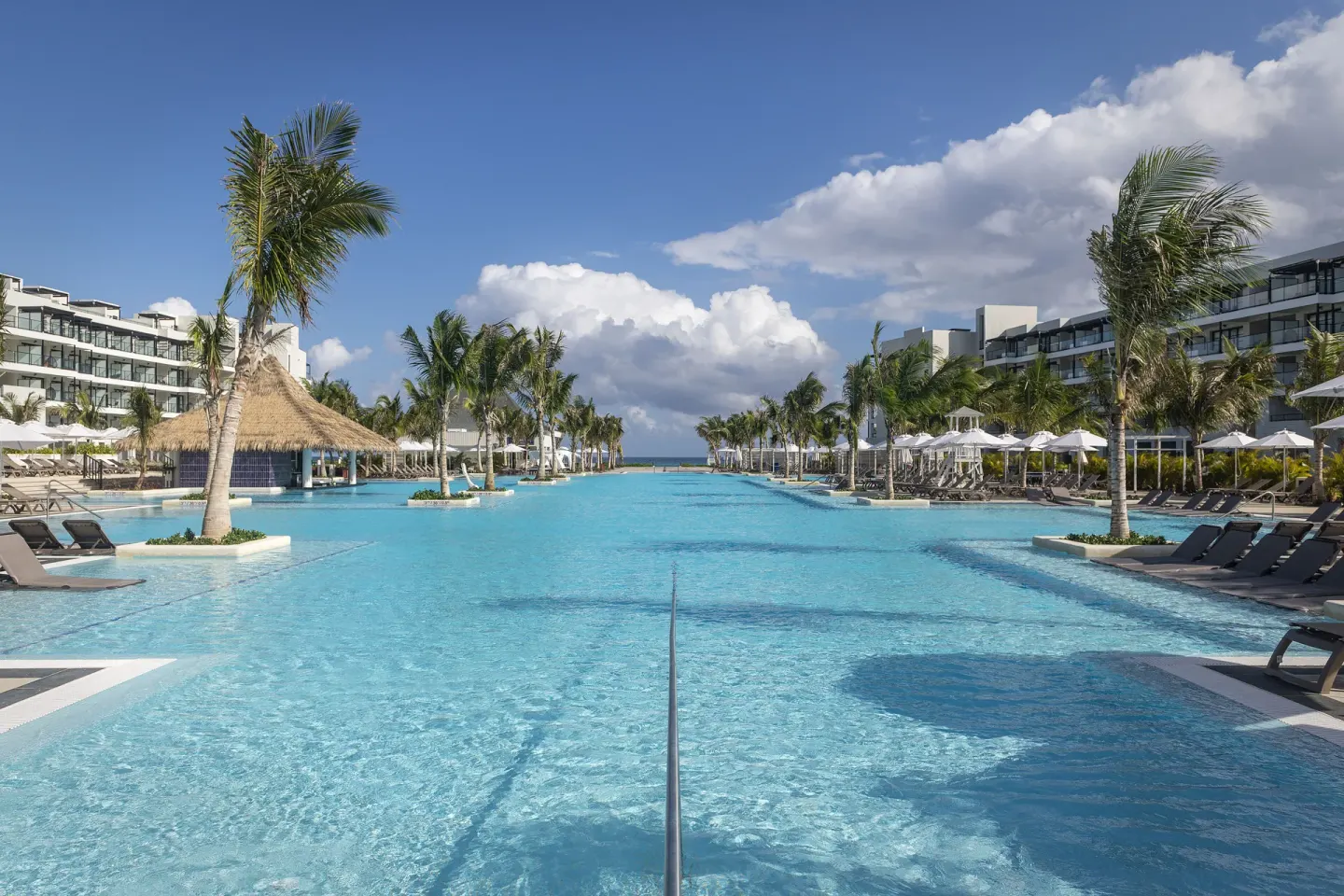 Resort pool with palms, loungers, and a thatched swim-up bar at Ocean Eden Bay.