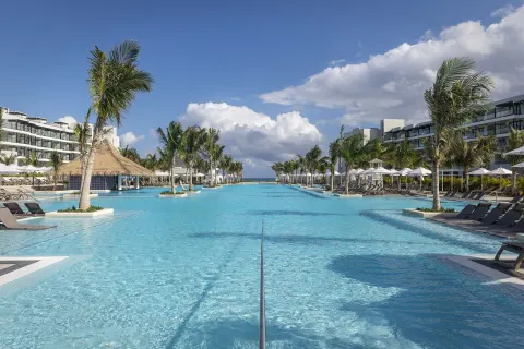 Resort pool with palms, loungers, and a thatched swim-up bar at Ocean Eden Bay.