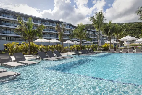 Poolside loungers and umbrellas in front of guest buildings at Ocean Eden Bay.