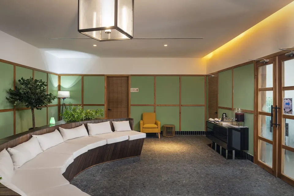 Spa lounge with curved white seating and green paneled walls at Ocean Eden Bay.