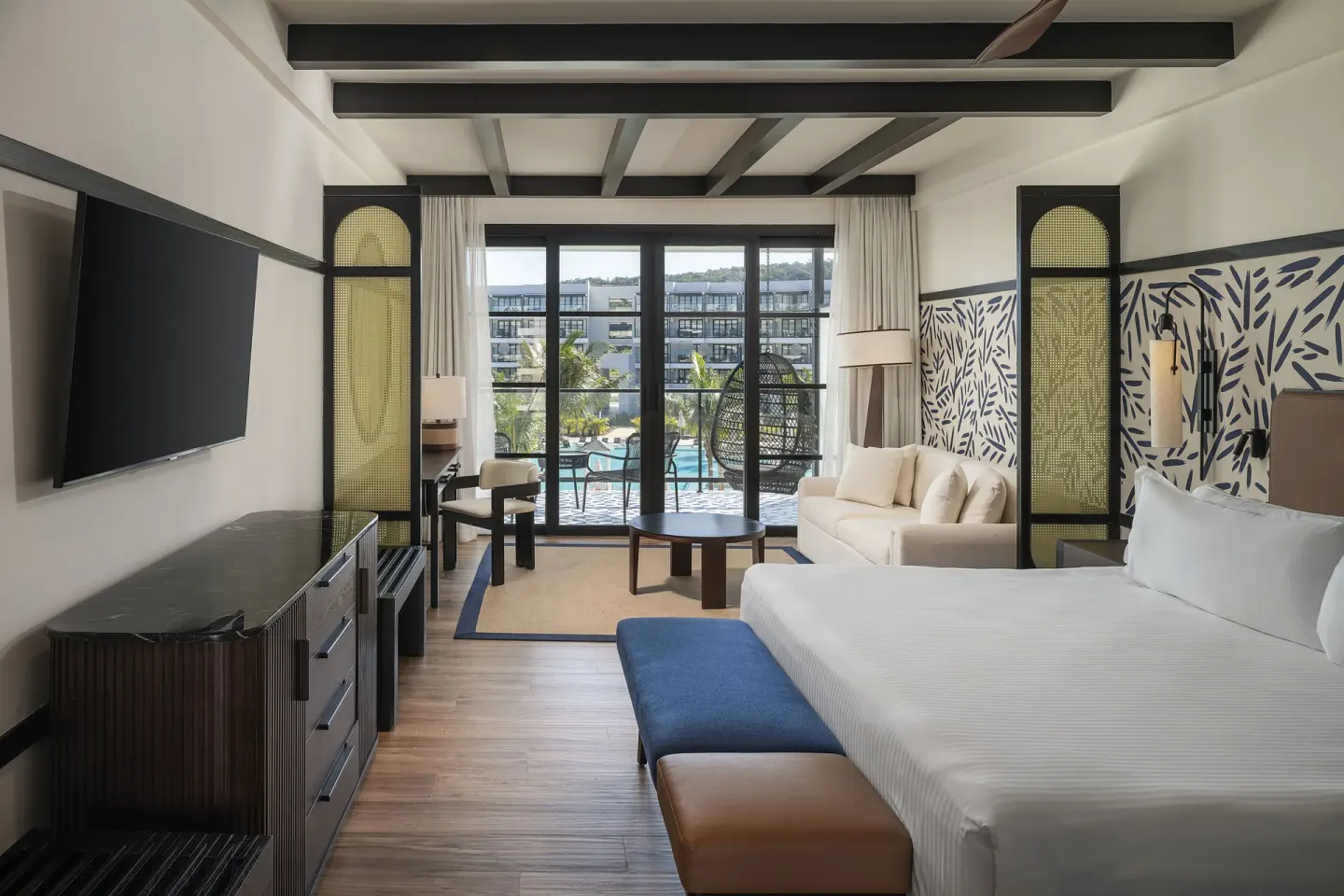 Junior Suite Pool View guest room with bed, sofa, balcony, and pool view at Ocean Eden Bay.