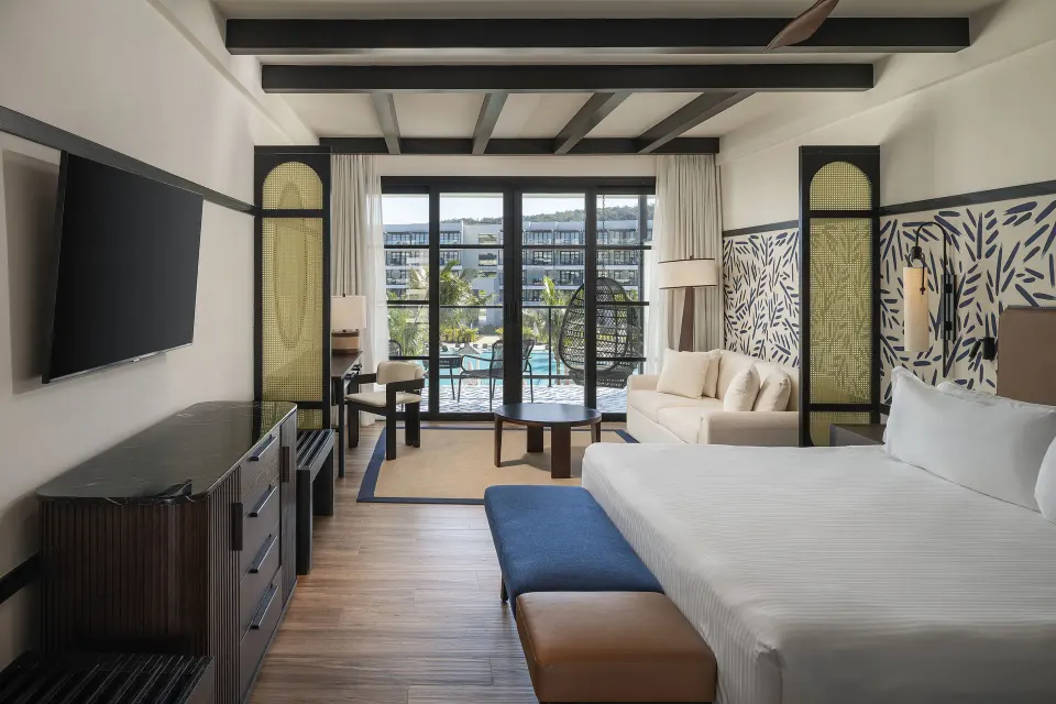 Junior Suite Pool View guest room with bed, sofa, balcony, and pool view at Ocean Eden Bay.