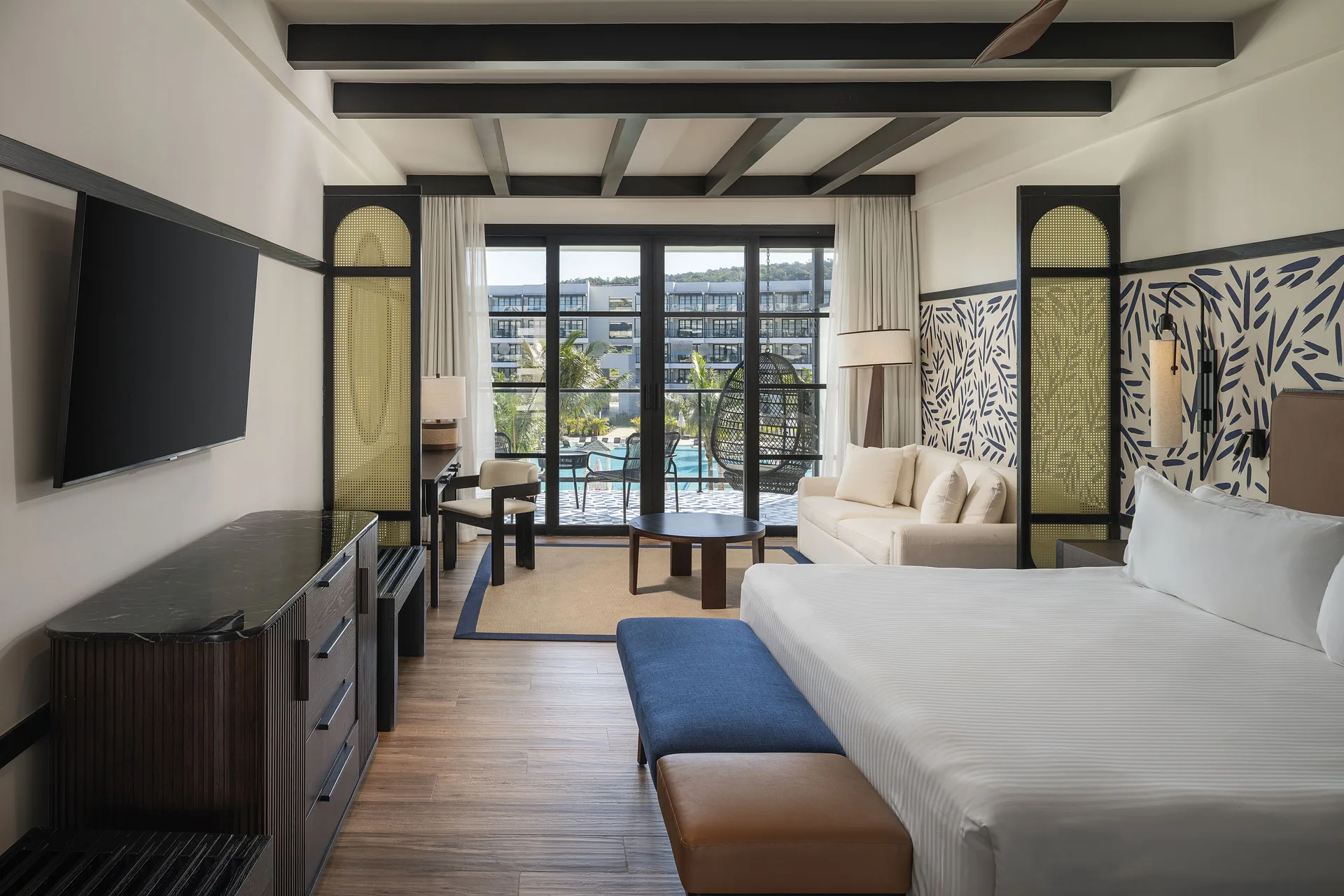 Junior Suite Pool View guest room with bed, sofa, balcony, and pool view at Ocean Eden Bay.