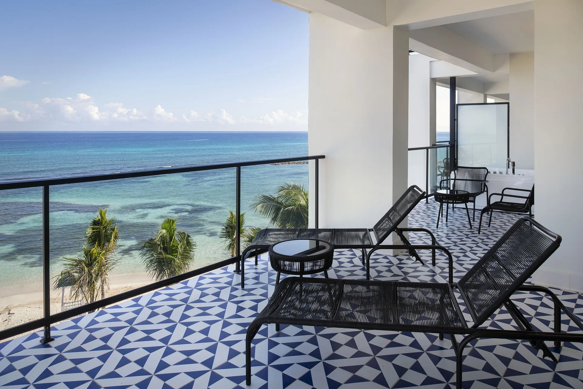 Privilege Master Suite Ocean Eden Bay balcony with loungers and sea view at Ocean Eden Bay.