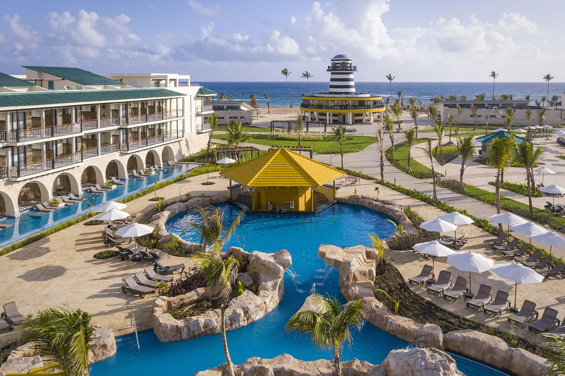 Aerial view of pool area and lighthouse near the ocean at Ocean El Faro Resort.