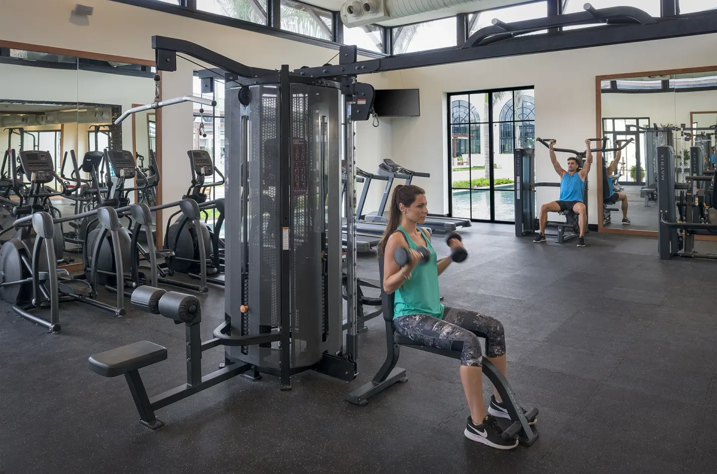 Guests using dumbbells and weight machines in the gym at Ocean El Faro Resort.