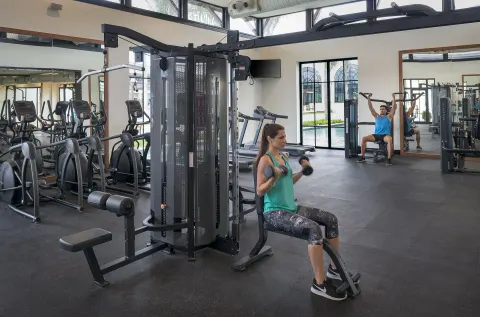 Guests using dumbbells and weight machines in the gym at Ocean El Faro Resort.