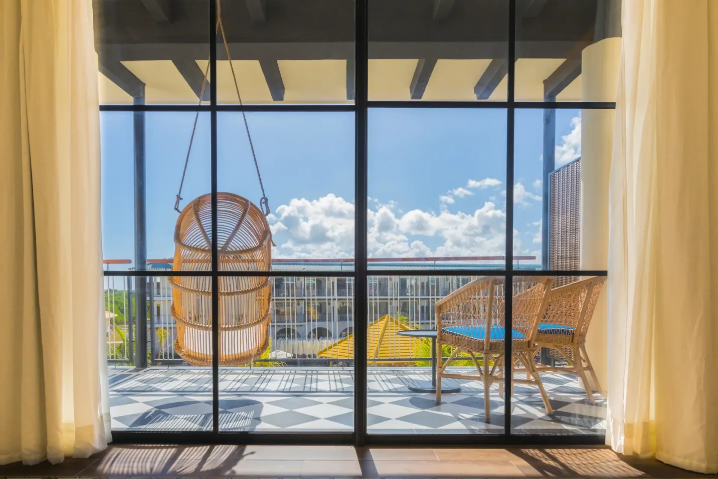Guest room balcony with hanging chair and outdoor seating at Ocean El Faro Resort.