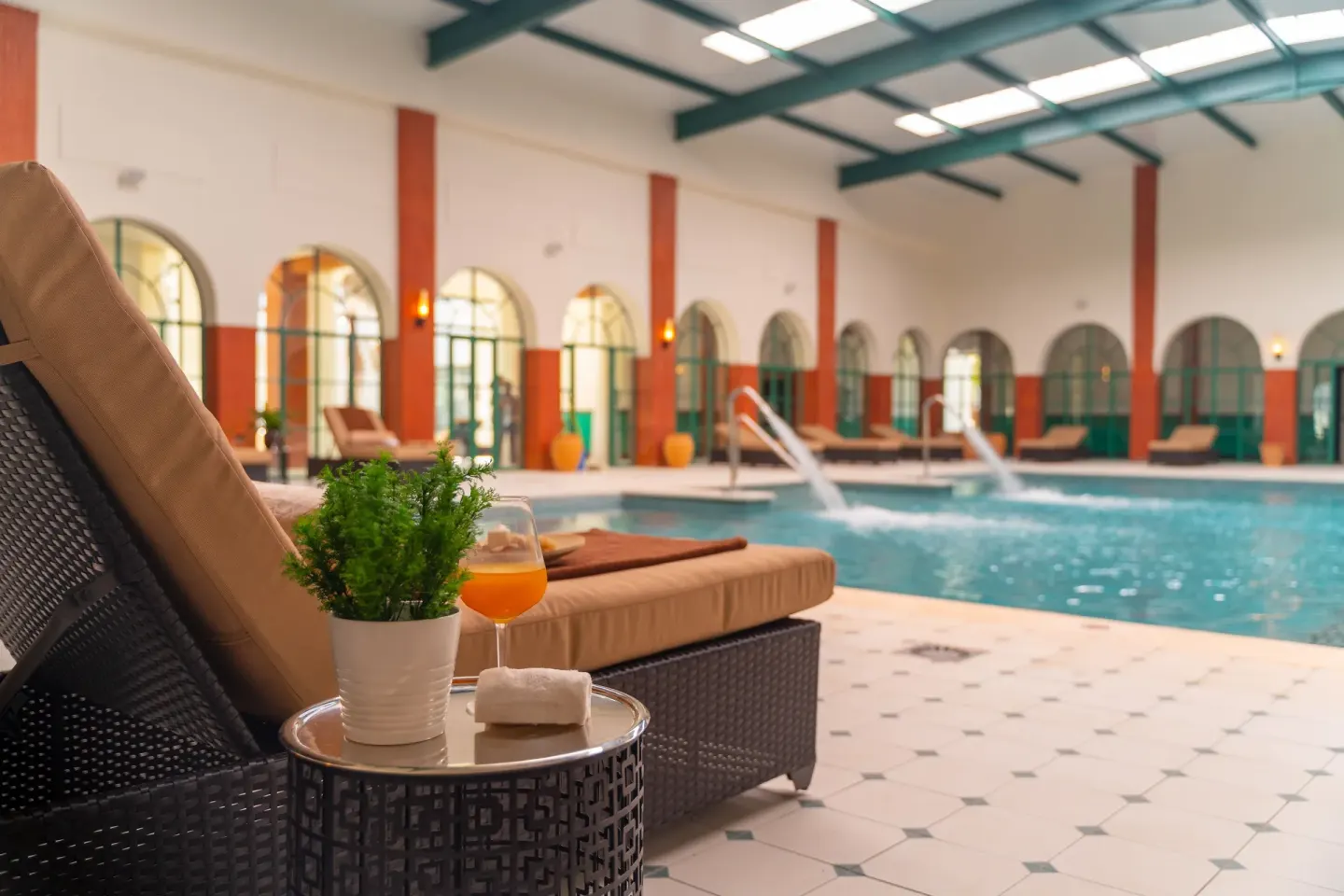 Indoor pool lounge chair with drink and plants at Ocean El Faro Resort.
