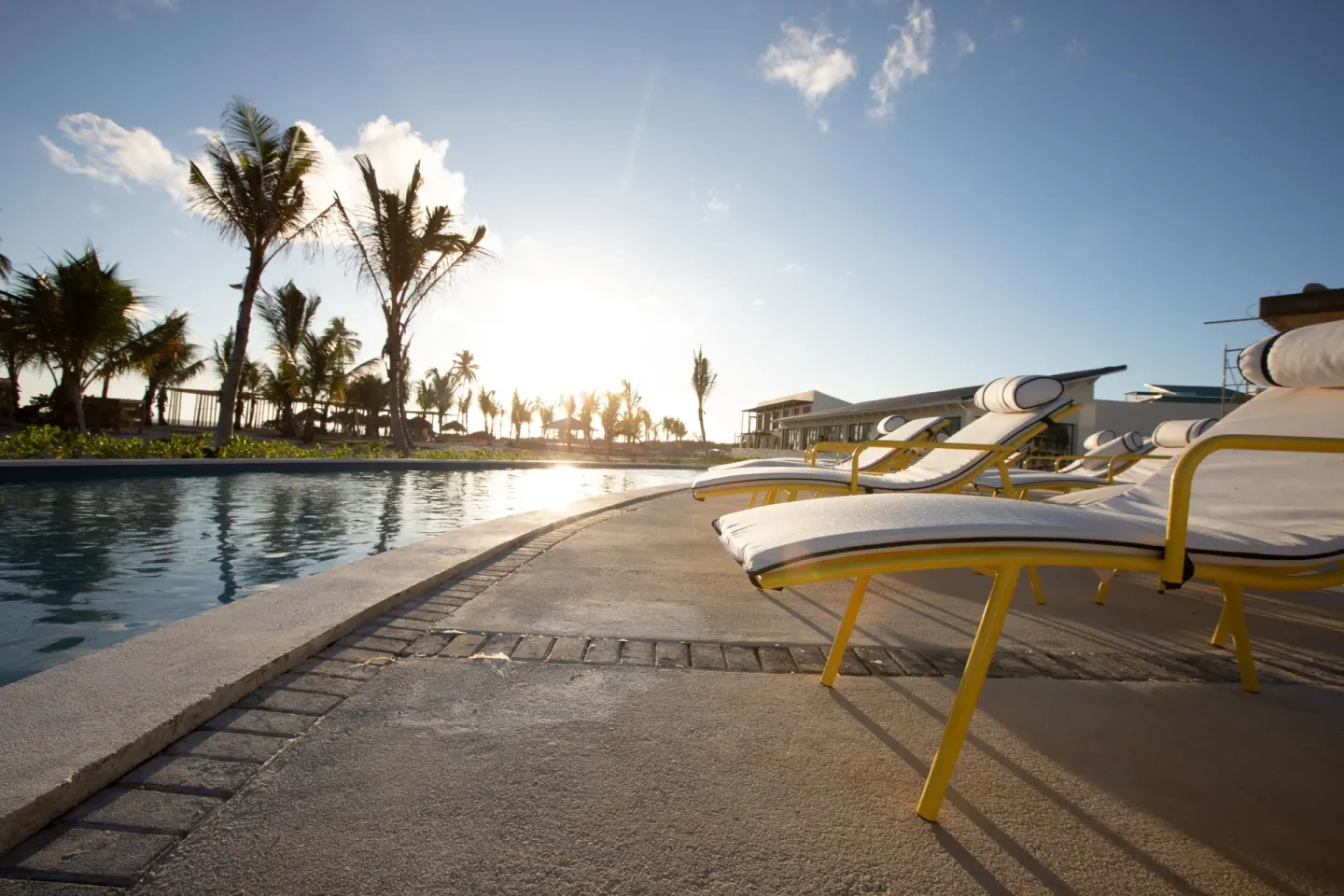 Poolside lounge chairs at sunset at Ocean El Faro Resort.