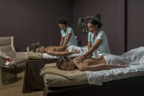 Two guests receiving massages in a spa treatment room at Ocean El Faro Resort.