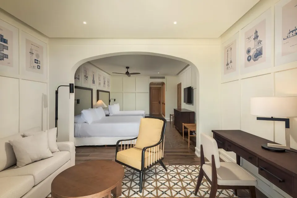 Junior Suite Nature View at Ocean El Faro Resort with sofa, desk, lounge chair, and two beds beyond.