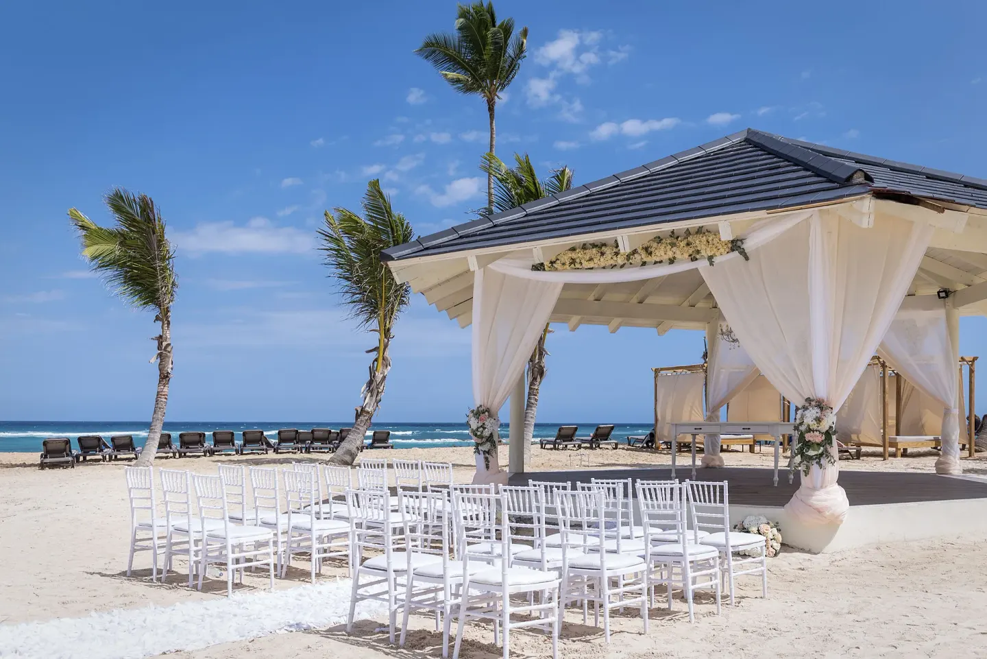 Beach wedding ceremony chairs and decorated gazebo at Ocean El Faro Resort.