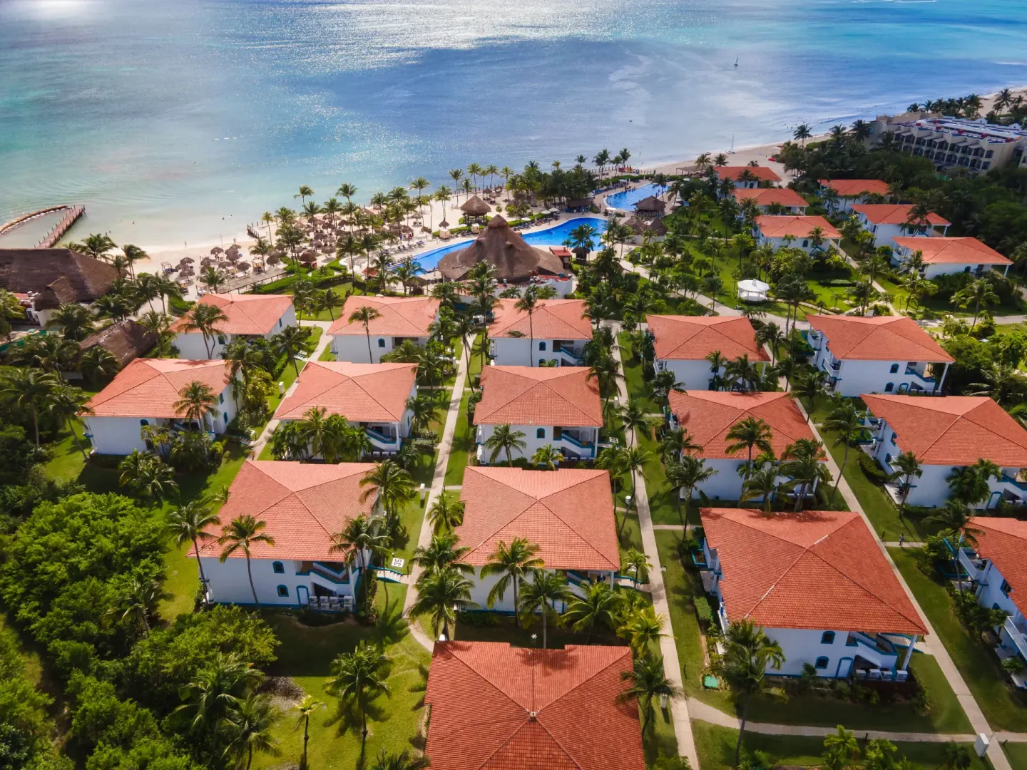 Aerial view of resort buildings, pools, gardens, and beach at Ocean Maya Royale.