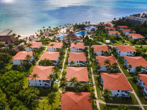 Aerial view of resort buildings, pools, gardens, and beach at Ocean Maya Royale.