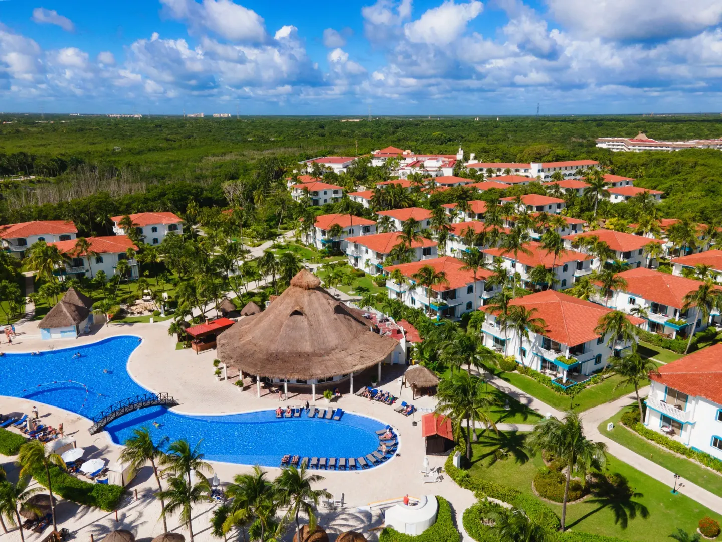 Aerial view of pools, thatched pavilion, gardens, and guest buildings at Ocean Maya Royale.
