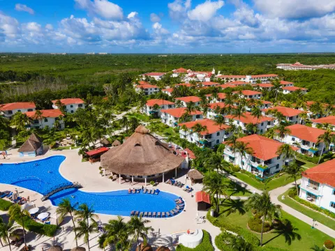 Aerial view of pools, thatched pavilion, gardens, and guest buildings at Ocean Maya Royale.