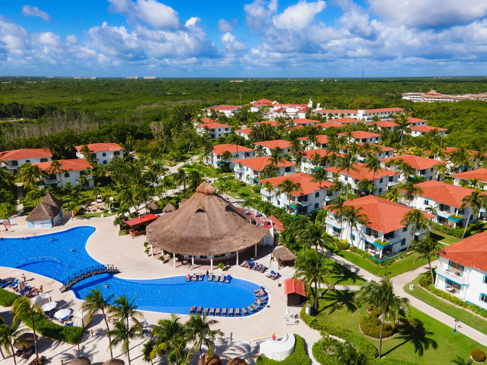 Aerial view of pools, thatched pavilion, gardens, and guest buildings at Ocean Maya Royale.
