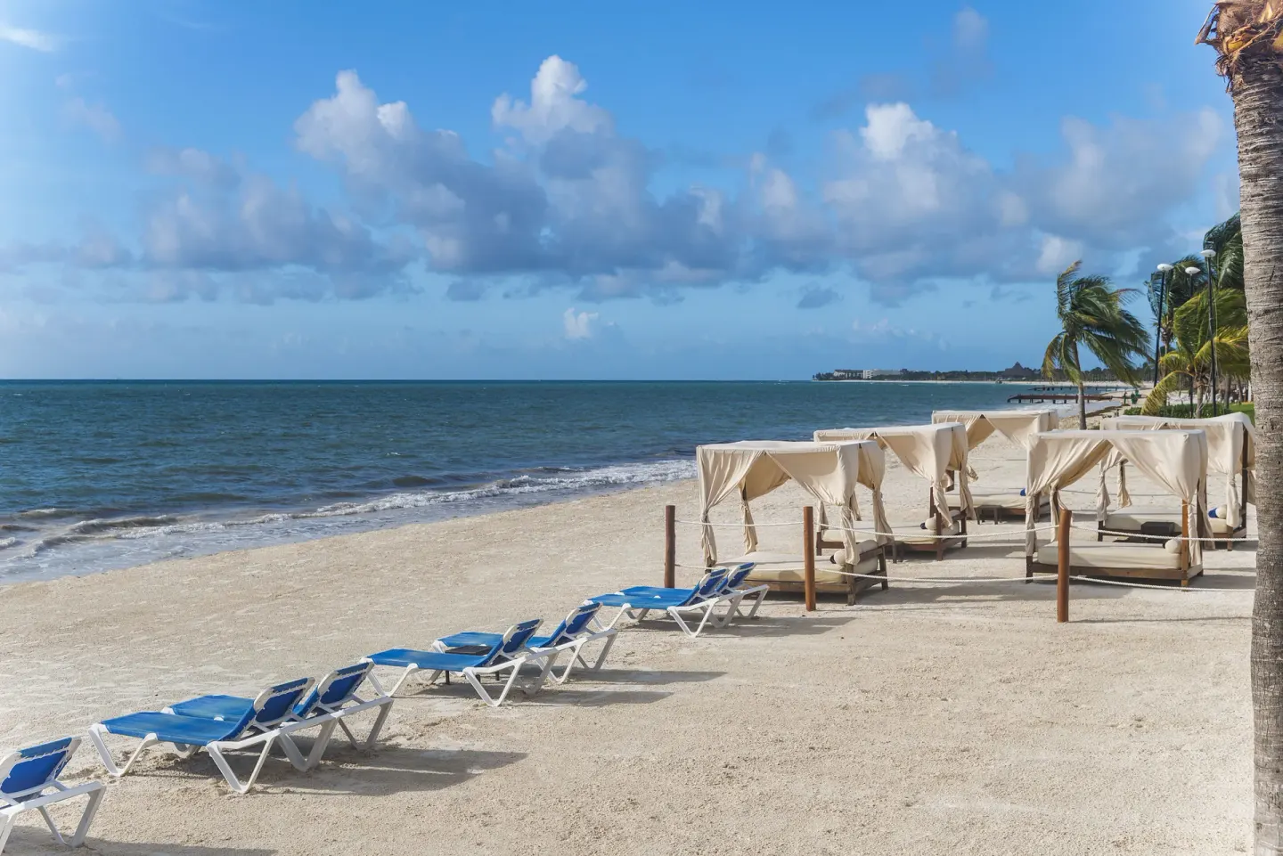 Blue lounge chairs and cabana beds line the beach at Ocean Maya Royale.