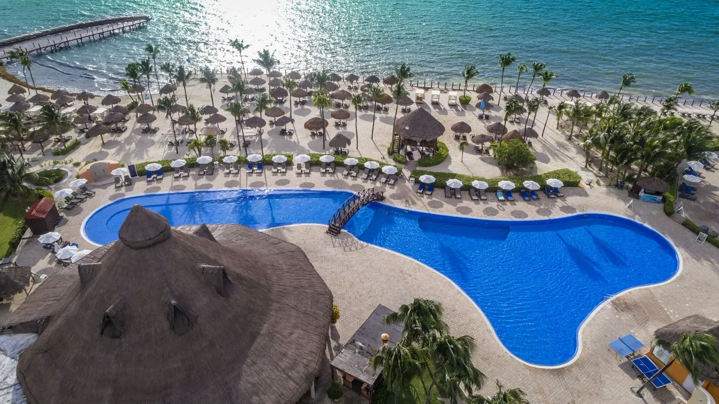 Beachfront pool with loungers, palapas, and sea views at Ocean Maya Royale.