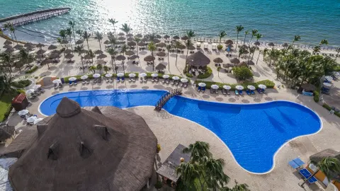 Beachfront pool with loungers, palapas, and sea views at Ocean Maya Royale.