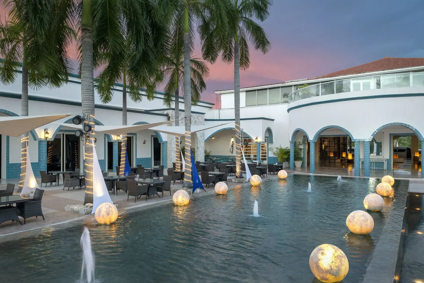 Palm-lined courtyard fountain and terrace seating at Ocean Maya Royale.