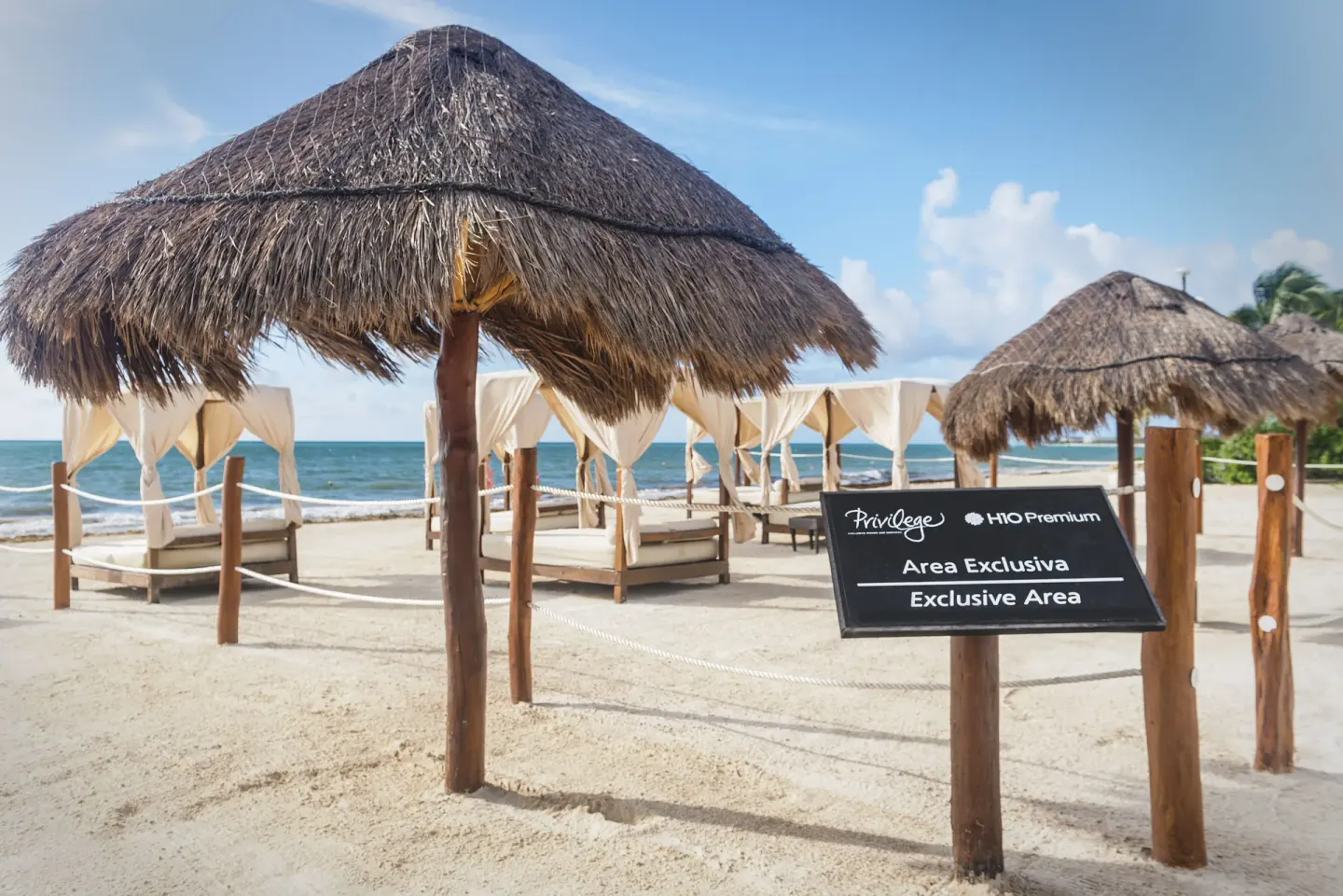 Thatched beach palapas and an exclusive-area sign at Ocean Maya Royale.