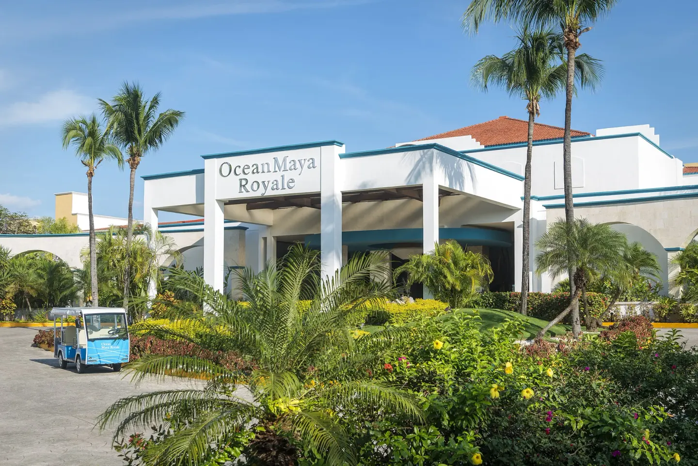Front entrance with resort sign and tropical landscaping at Ocean Maya Royale.