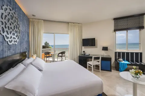 Ocean-view guest room with king bed and balcony at Ocean Maya Royale.