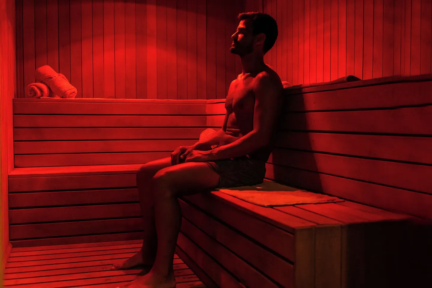Guest sits in a red-lit wood sauna at Ocean Maya Royale.