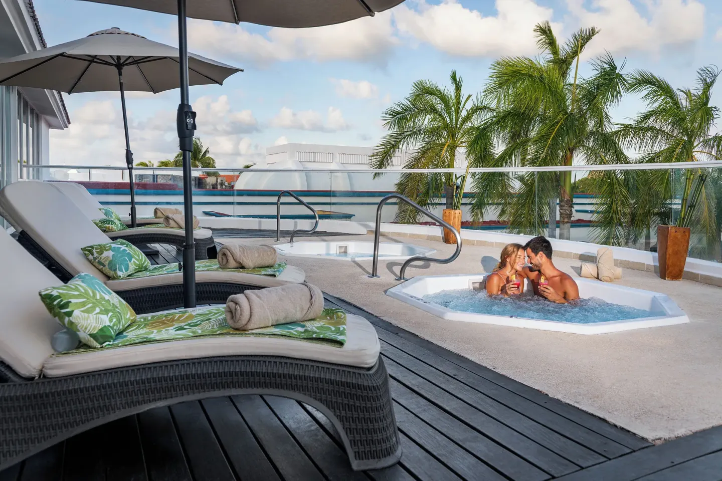 Rooftop plunge pool and loungers with palm views at Ocean Maya Royale.