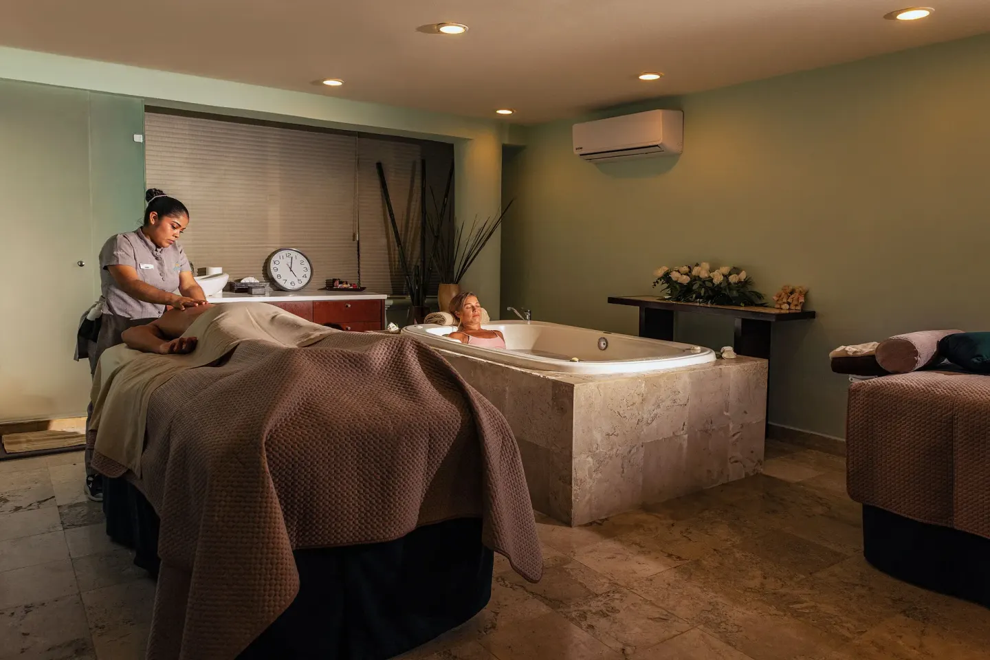 Spa treatment room with massage bed and soaking tub at Ocean Maya Royale.