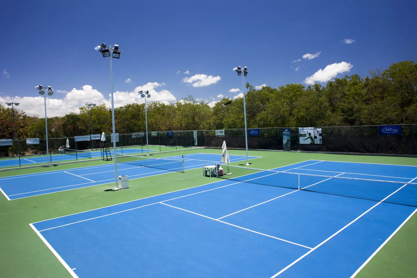 Blue and green tennis courts under a clear sky at Ocean Maya Royale.