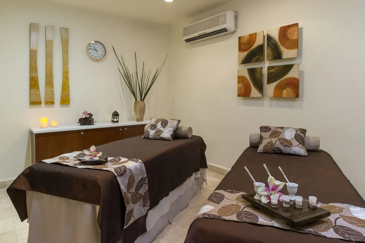 Twin spa treatment beds with candles and floral accents at Ocean Maya Royale.
