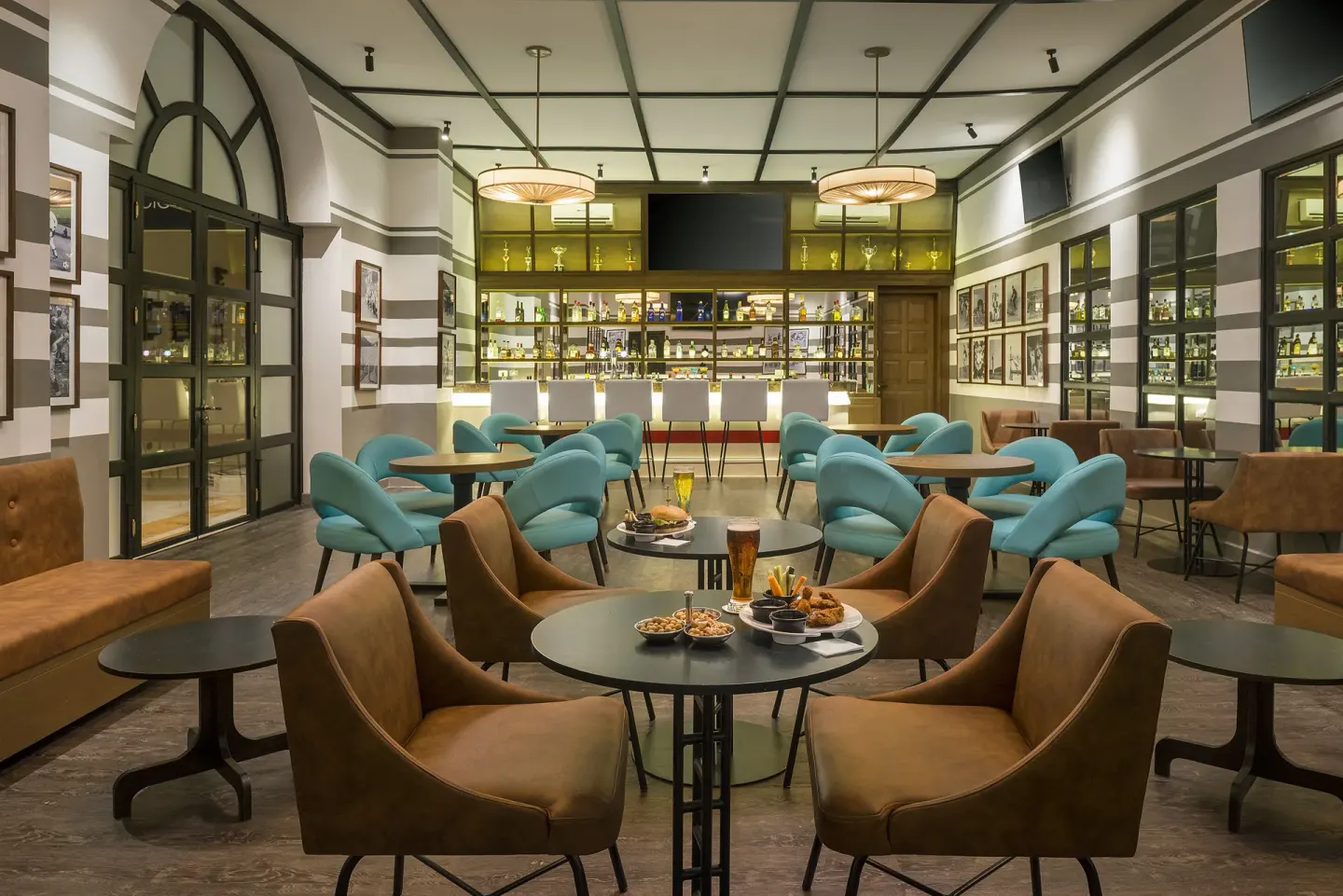 Sports Bar lounge with turquoise chairs, tables, and back bar at Ocean Maya Royale.