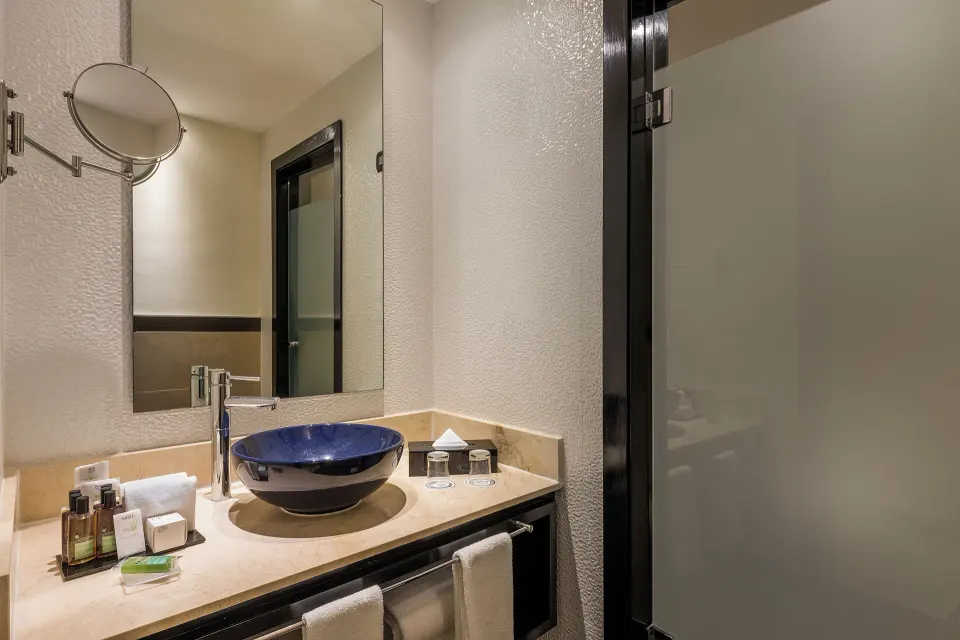 Junior Suite Nature View bathroom vanity with blue vessel sink at Ocean Maya Royale.