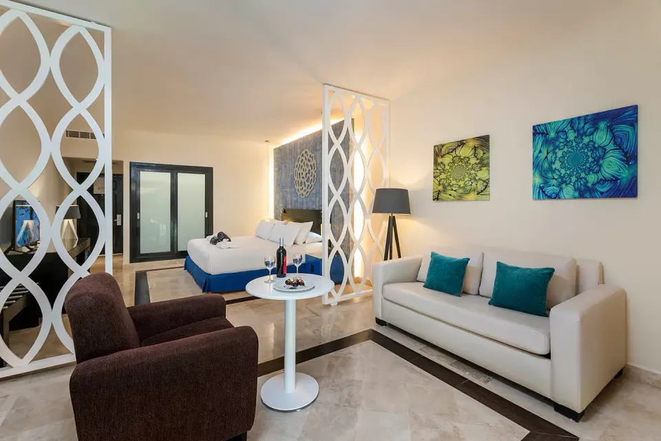 Room Luxury seating area and king bed at Ocean Maya Royale with sofa, table, and decorative screens.