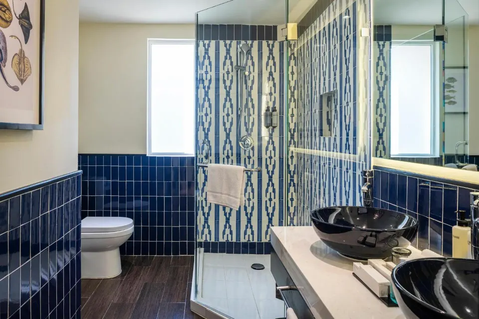 Junior suite bathroom with glass shower and blue tile at Ocean Maya Royale.