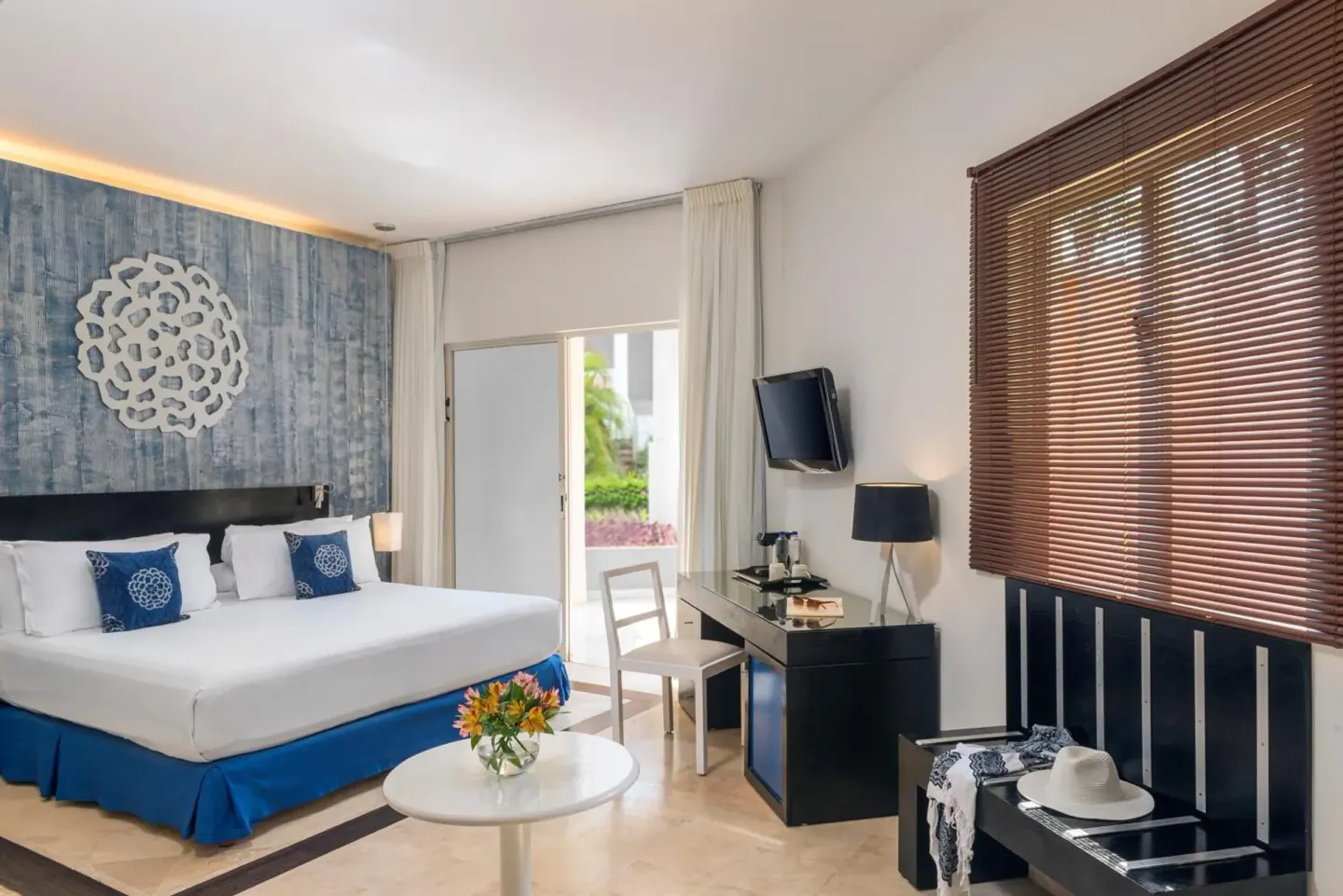 Junior suite king bed with terrace doors and desk at Ocean Maya Royale.