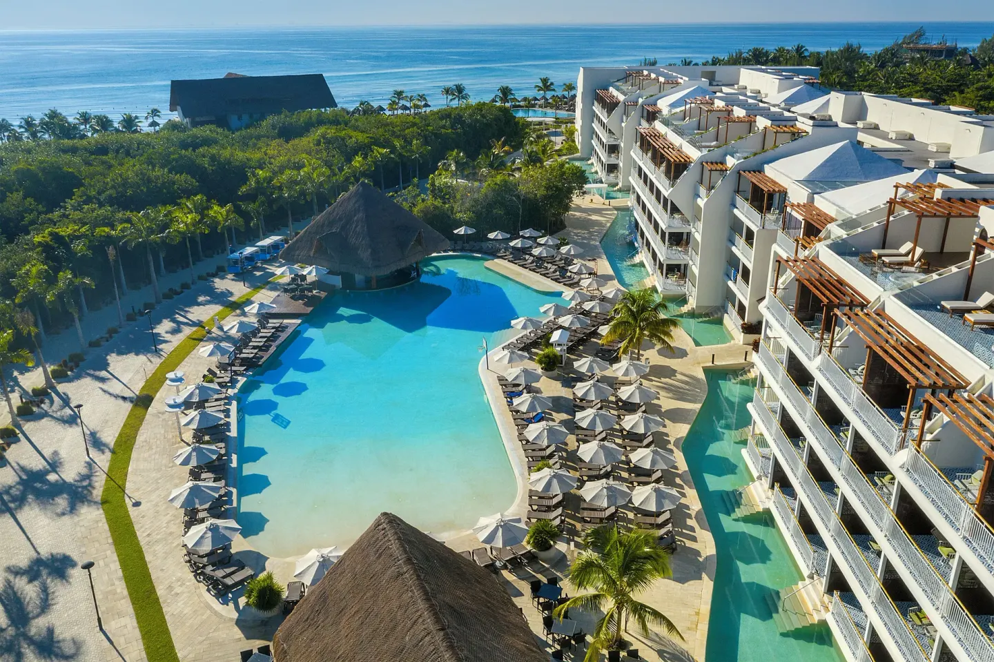 Aerial view of pools, buildings, palm trees, and ocean at Ocean Riviera Paradise.