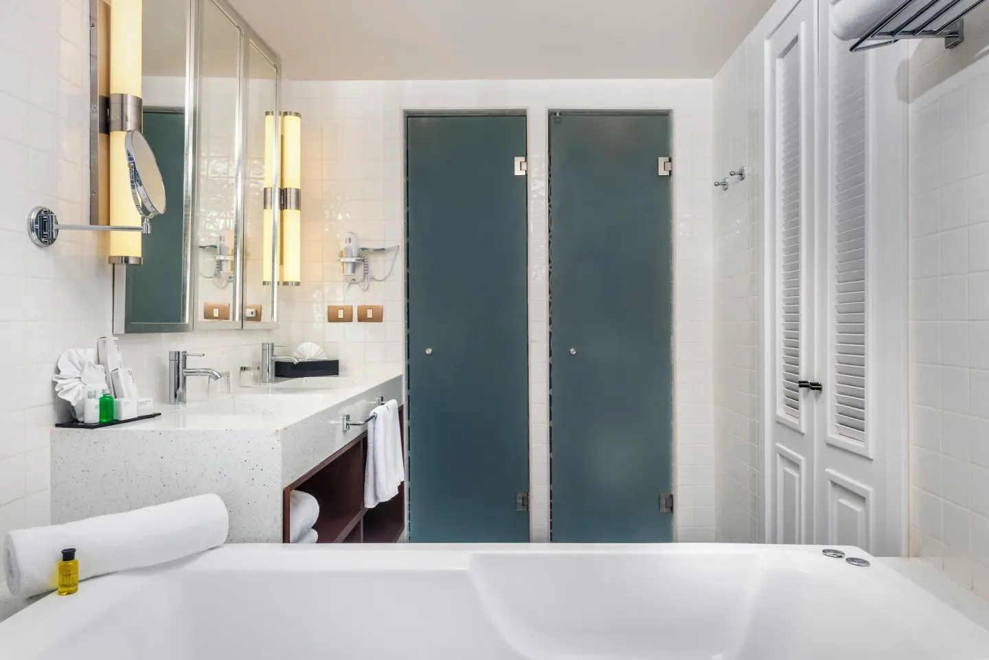Bathroom with bathtub, vanity, frosted shower doors, and towel storage at Ocean Riviera Paradise.