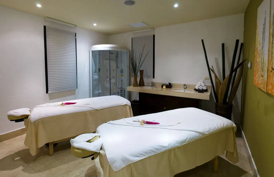 Spa treatment room with two massage tables and a shower at Ocean Riviera Paradise.