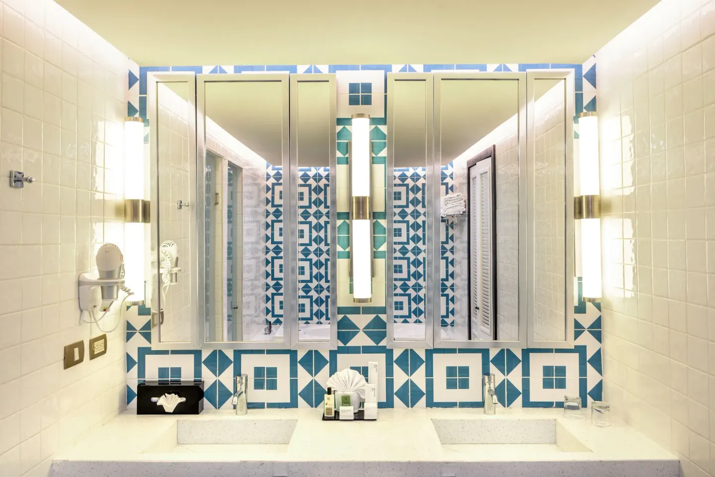 Double-sink bathroom vanity with tall mirrors and blue tile at Ocean Riviera Paradise.