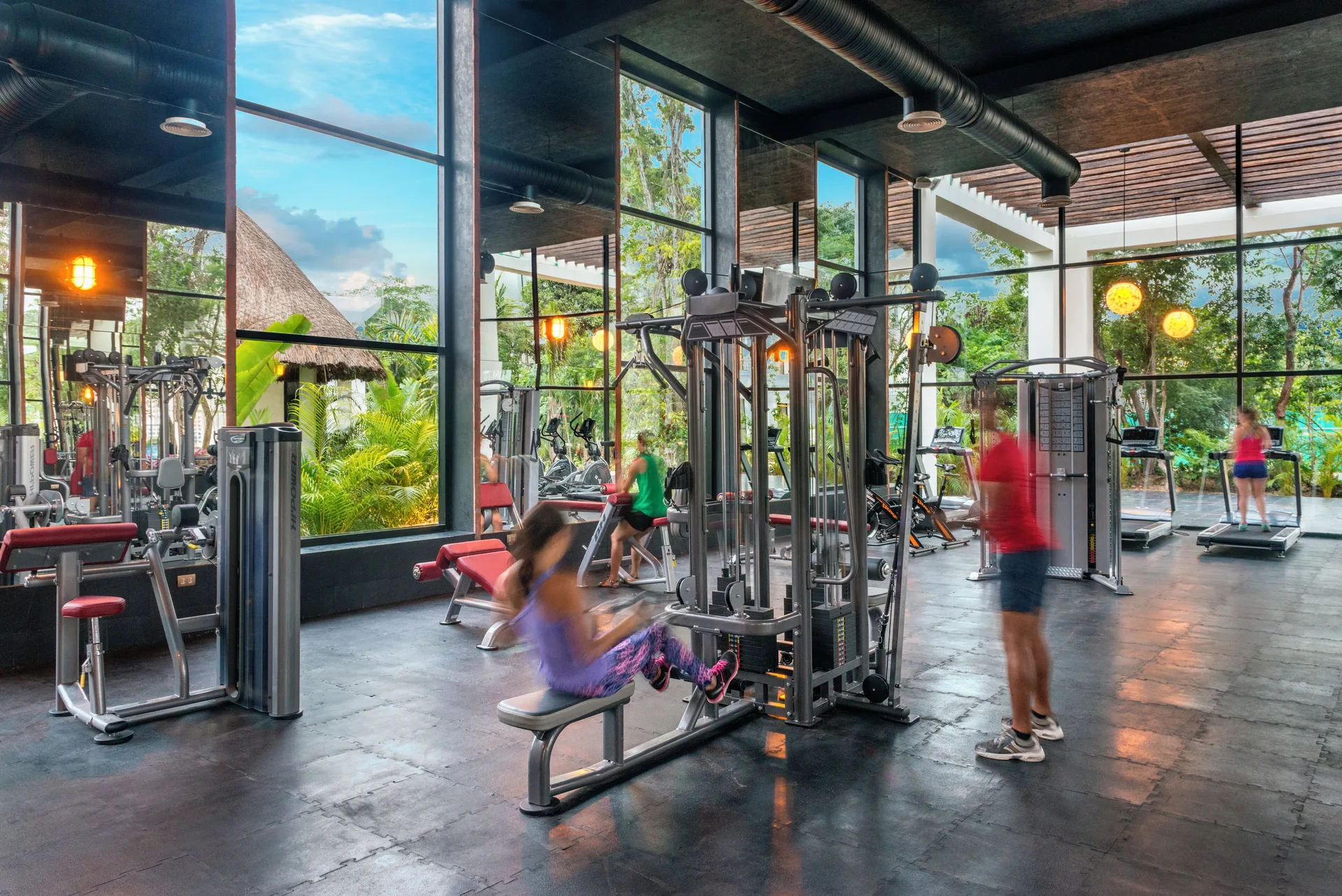 Fitness center with weight machines, treadmills, and tall windows at Ocean Riviera Paradise.