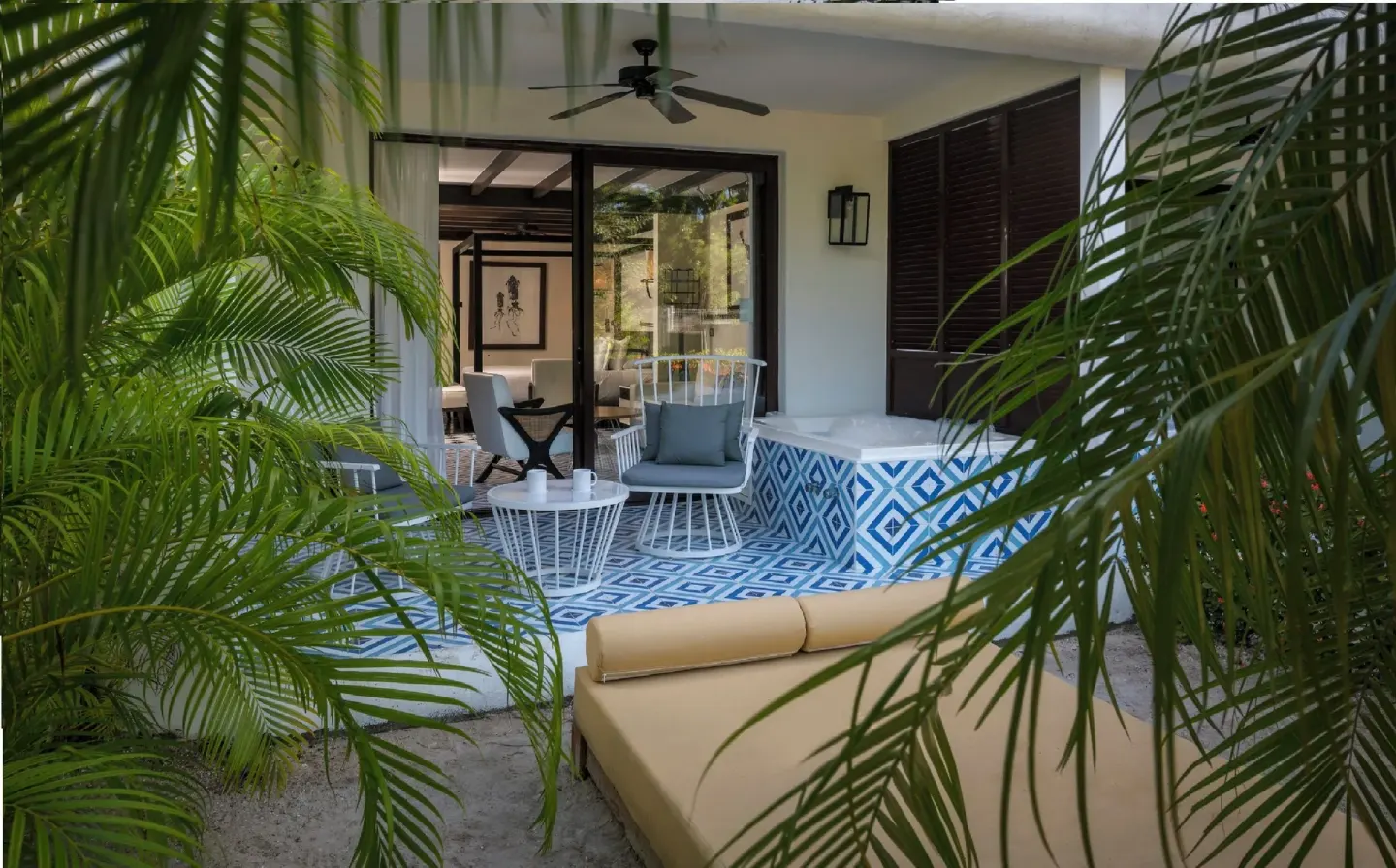 Garden-level terrace with hot tub, chairs, and daybed at Ocean Riviera Paradise.