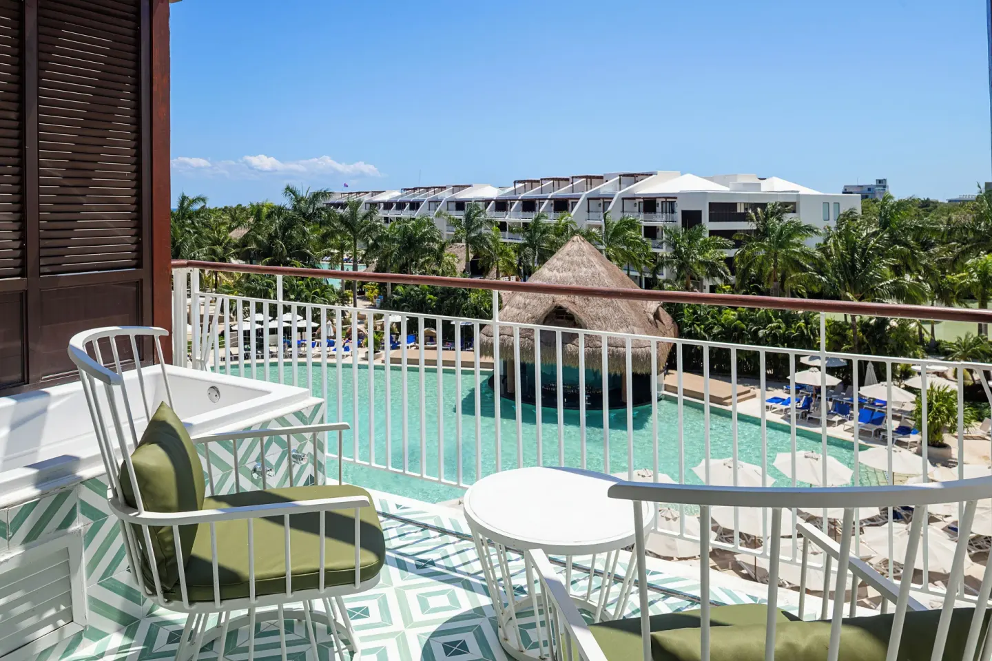 Guest room balcony with pool and palm views at Ocean Riviera Paradise.