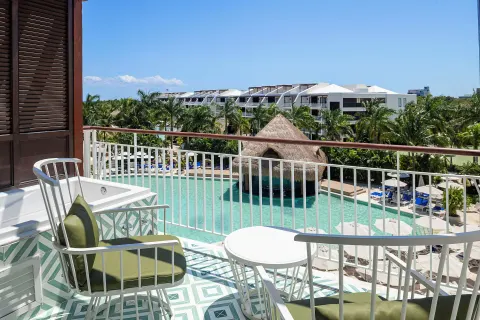 Guest room balcony with pool and palm views at Ocean Riviera Paradise.