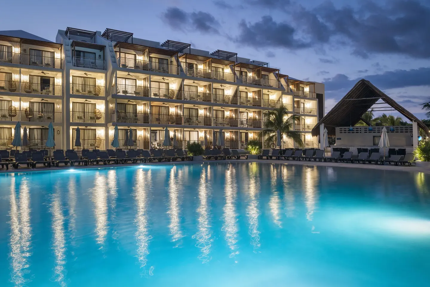 Illuminated pool and resort building at dusk at Ocean Riviera Paradise.